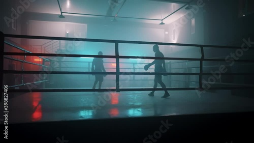 Boxer in the boxing gym. Bandages his hands. Sparring in the ring. Boxer jumping rope. Exercise with ropes. Round one. Fog in the ring. Zetsky sport. Beautiful backlight. World boxing champion.

 photo