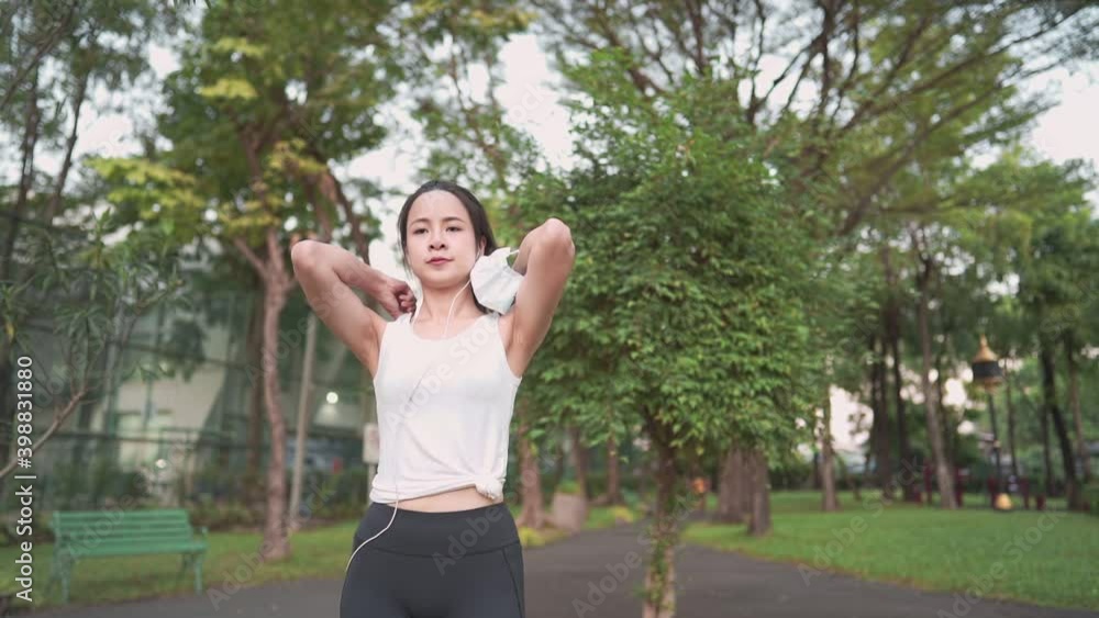 Follow up view of sportive asian young black hair woman running through camera in city park on public green background, fit attractive pretty woman jogging at outdoor workout on background of trees, h