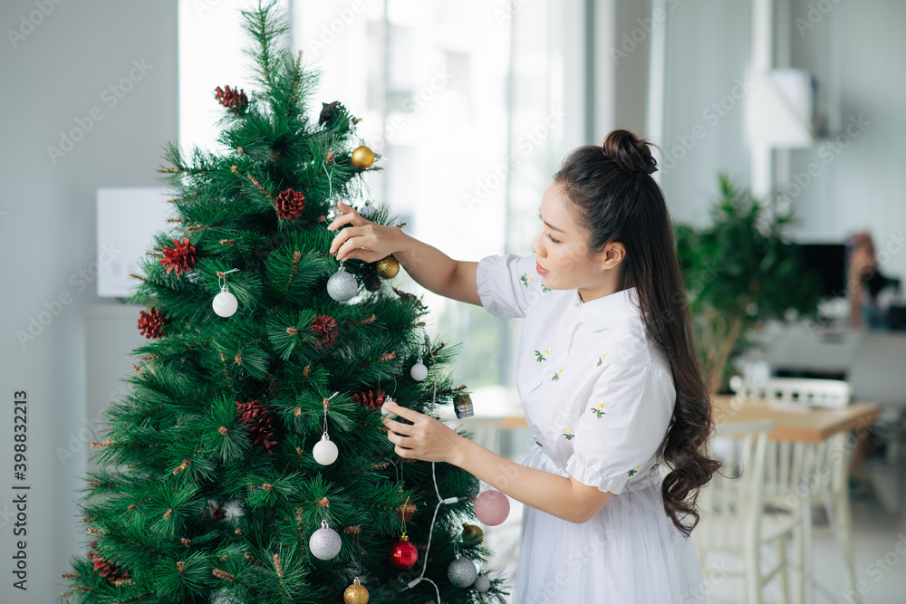 young woman decorating a Christmas tree. Holidays and celebrations concept young woman decorating a Christmas tree. Holidays and celebrations concept