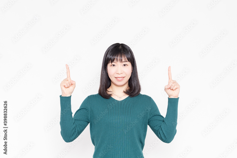 白背景の前に立って人差し指でポイントを示す女性 白背景の前に立って人差し指でポイントを示す女性