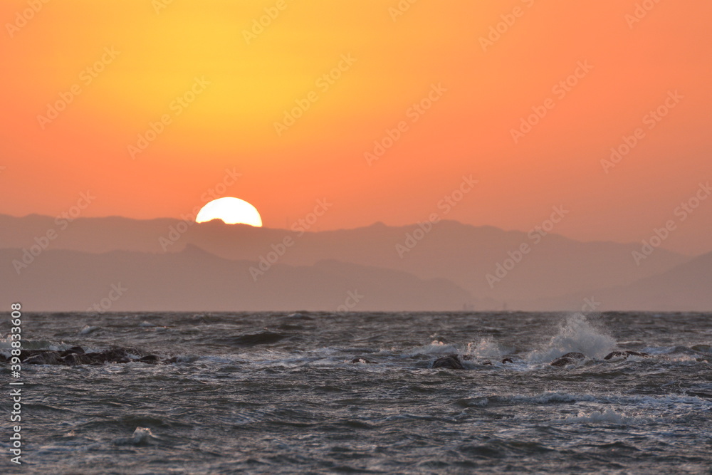 海の先に空をオレンジに染めながら沈む夕日