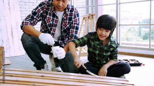 Young male carpenter teaching his son how to work with wood in workshop.