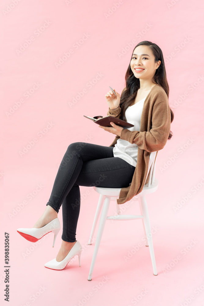happy smiling asian woman with diary sitting in chair happy smiling asian woman with diary sitting in chair