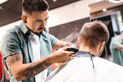 Professional hairdresser working with client in barbershop