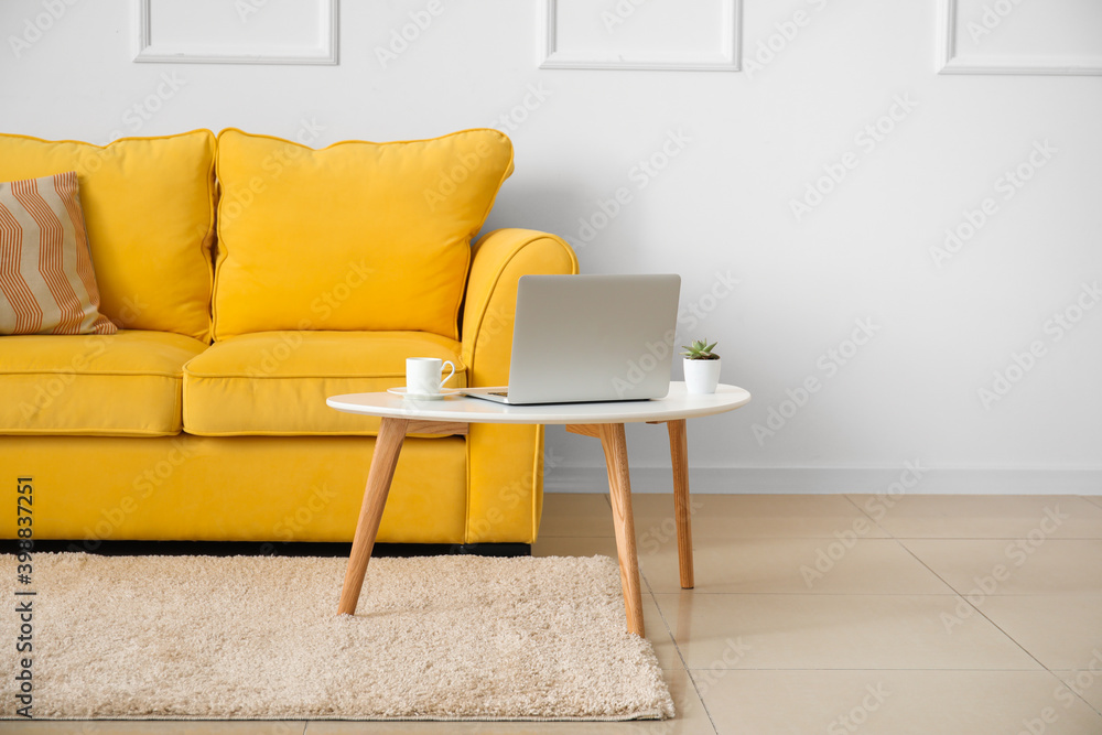Stylish sofa and laptop near light wall in room Stylish sofa and laptop near light wall in room