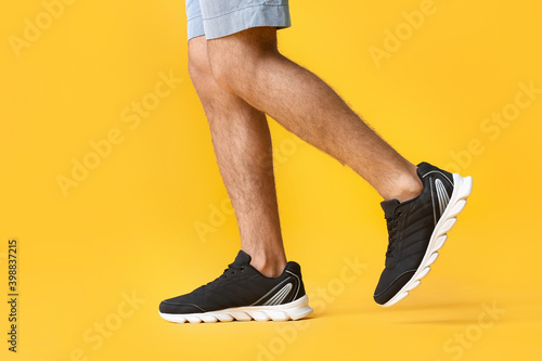 Young man in sportive shoes on color background