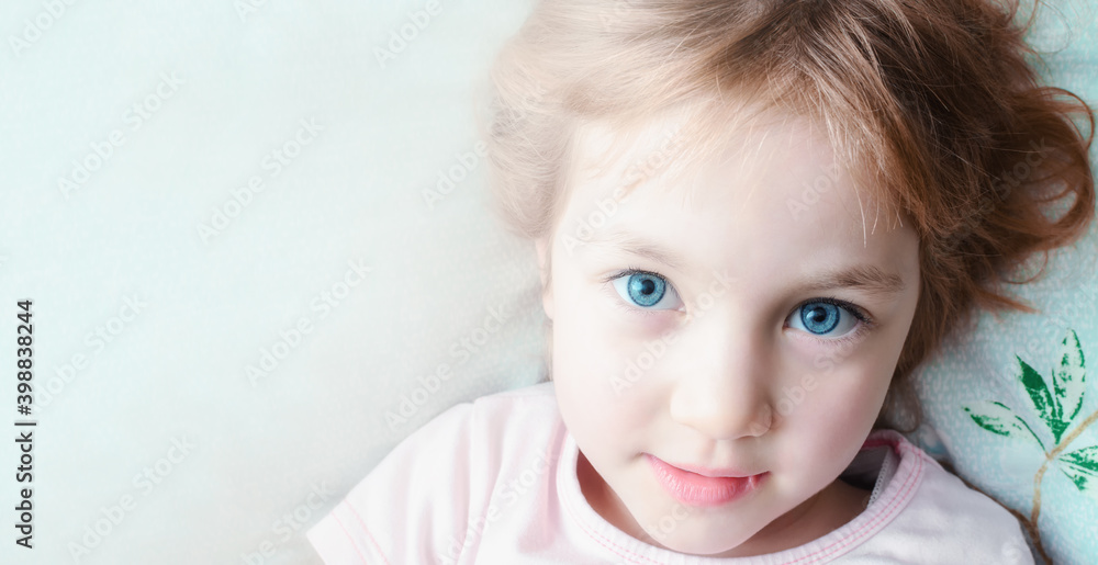 Beautiful child with big eyes is lying on pillow in the bedroom. Beautiful child with big eyes is lying on pillow in the bedroom.