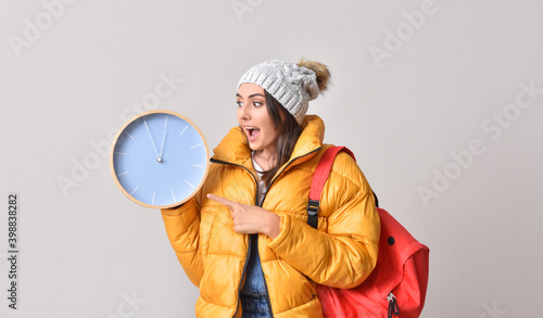 Female student with clock on grey background