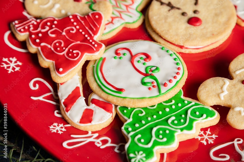 Red plate full of colorfully decorated Christmas cookies - Christmas eve recipes - Christmas holiday culinary traditions