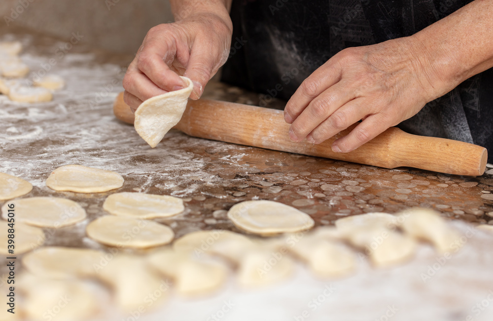 Woman rolls the dough with a rolling pin on the table. Woman rolls the dough with a rolling pin on the table.