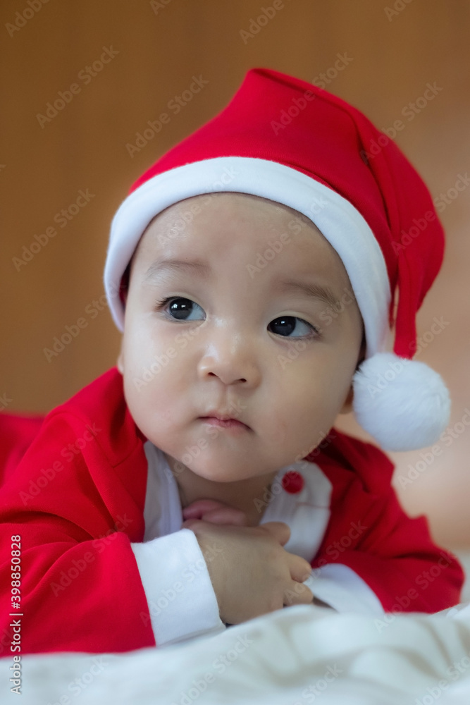 Christmas and New Year funny happy curious Asian infant baby in Santa Claus clothes Christmas and New Year funny happy curious Asian infant baby in Santa Claus clothes