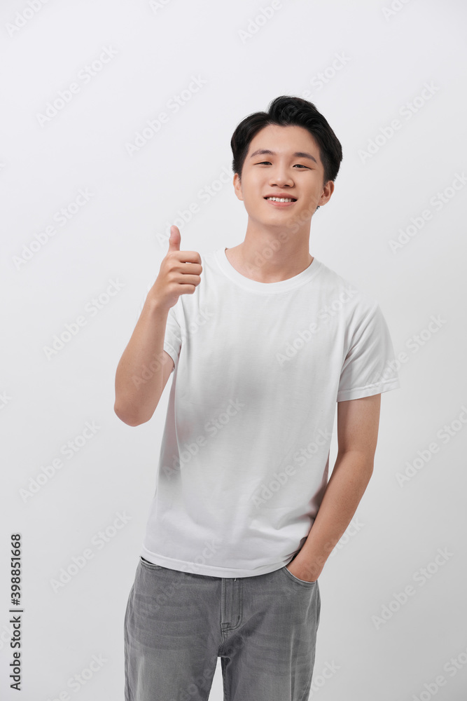 Smiling young handsome casual Asian man giving thumbs up studio shot isolated on white background Smiling young handsome casual Asian man giving thumbs up studio shot isolated on white background