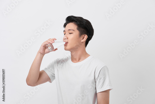 Healthy and happy young man drinking water while relaxing at home