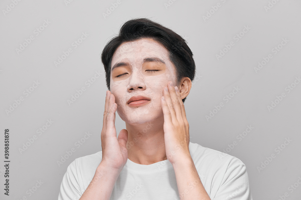 Handsome man with clay mask on his face against color background Handsome man with clay mask on his face against color background