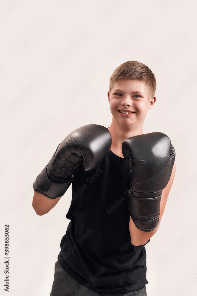 Portrait of cheerful disabled boy with Down syndrome wearing big boxing gloves, smiling at camera while posing isolated over white background Portrait of cheerful disabled boy with Down syndrome wearing big boxing gloves, smiling at camera while posing isolated over white background