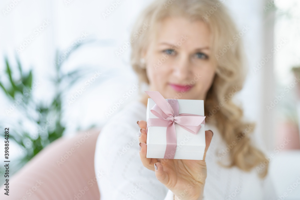 A woman holds a jewelry box with a pink bow in her hands. Bracelet with charms. A gift for any occasion. A woman holds a jewelry box with a pink bow in her hands. Bracelet with charms. A gift for any occasion.