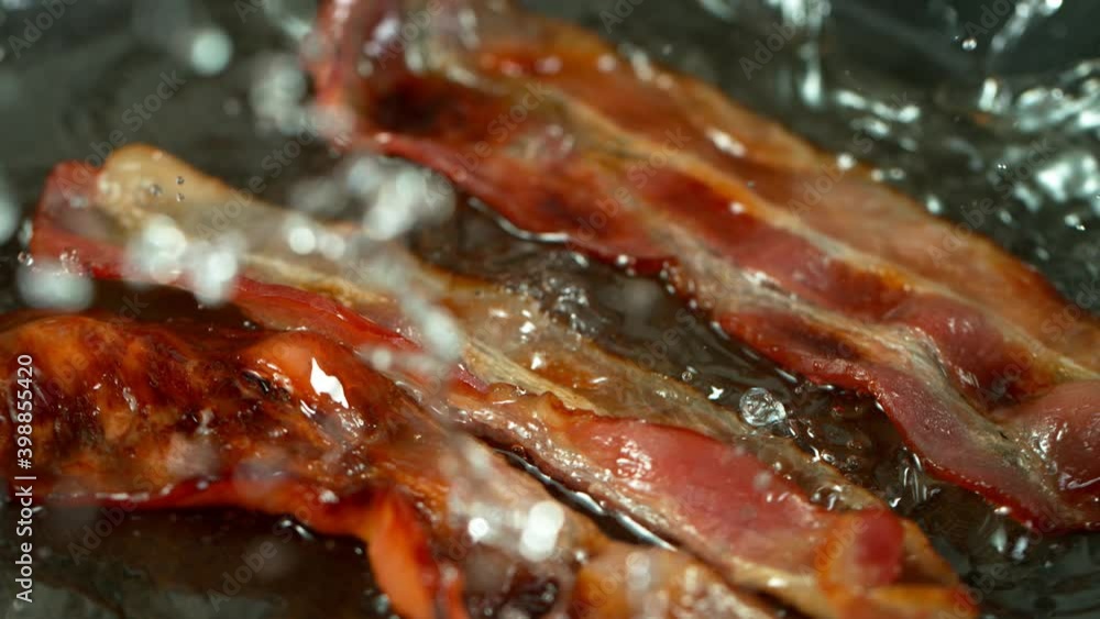 Super Slow Motion Shot of Roasted Bacon Slices Falling into Pan at 1000 fps. Super Slow Motion Shot of Roasted Bacon Slices Falling into Pan at 1000 fps.