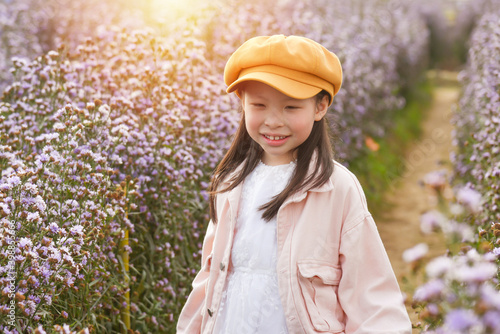Young beautiful asian girl child smiling while walking through purple flower field.