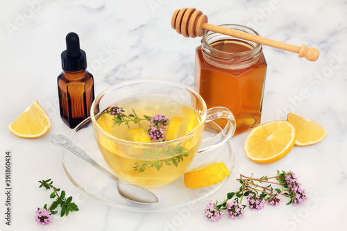 Healing thyme herb & lemon hot drink for cold and flu virus in a glass tea cup with honey and essential oil. Immune boosting medication, is anti bacterial, antiseptic and anti viral. On marble.