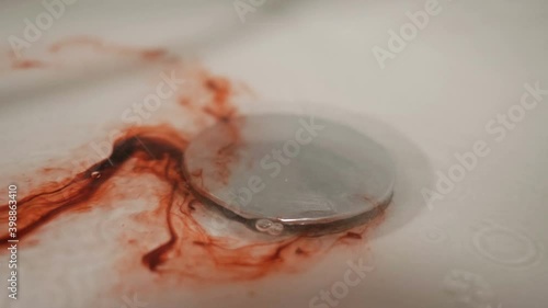 Blood with water flows down the drain hole in the shower. Metaphor.