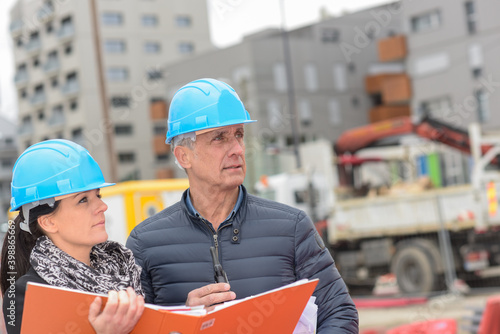 Фотография Construction manager and architect read their notes on a building site