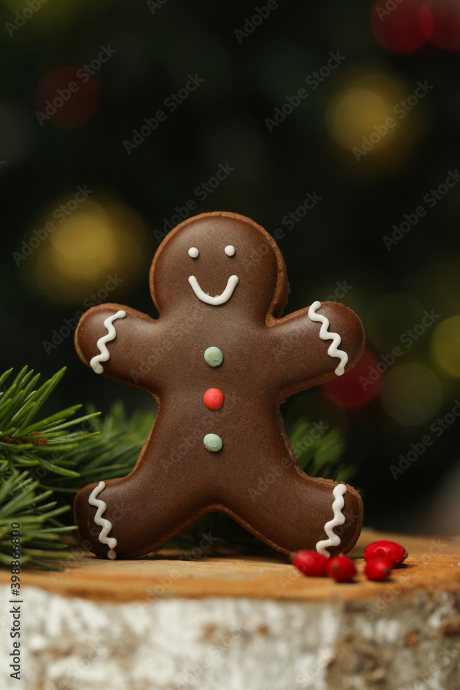 Gingerbread man cookie in festive Christmas arrangement with bokeh lights in background.