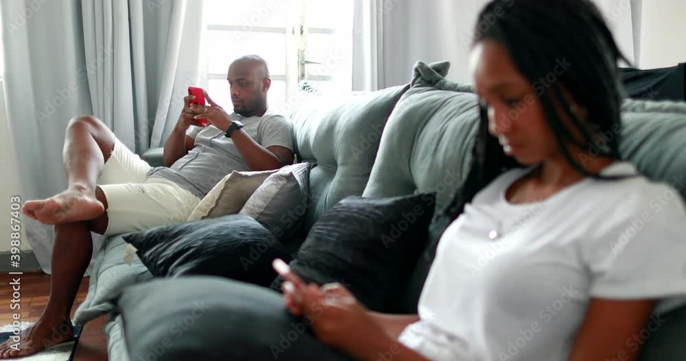 People at home looking at their cellphones. African american father and teen daughter using smartphone People at home looking at their cellphones. African american father and teen daughter using smartphone