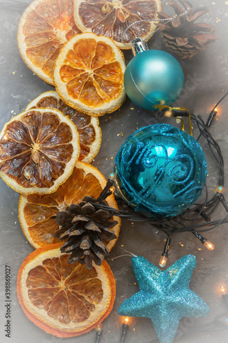 Round slices of dry orange and lemon with garland lights on gray dark background. Top view, selective focus, fog view