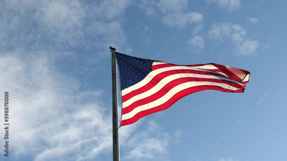 American flag waving with the wind with a blue sky as background American flag waving with the wind with a blue sky as background