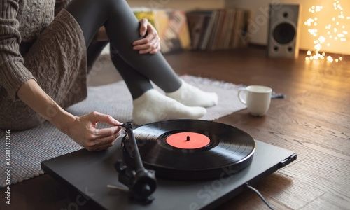 Young woman listening to music, relaxing, enjoying life at home. Girl wearing warm winter clothes having fun. Turntable playing vinyl LP record. Leisure, music, hobby, lockdown, lyfestyle concept photo