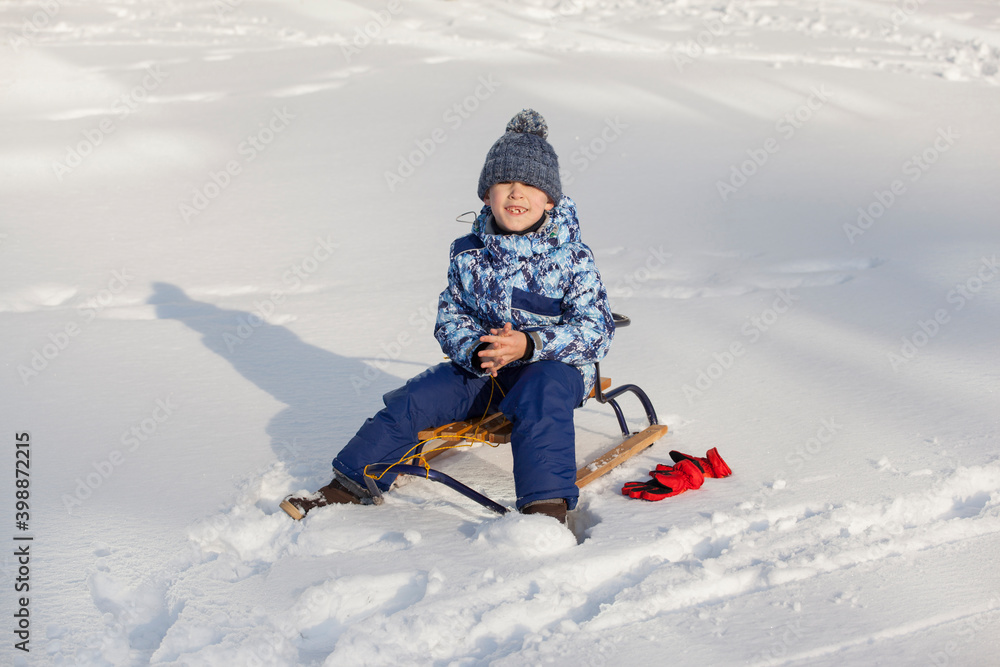 little boy in winter clothes with sleigh