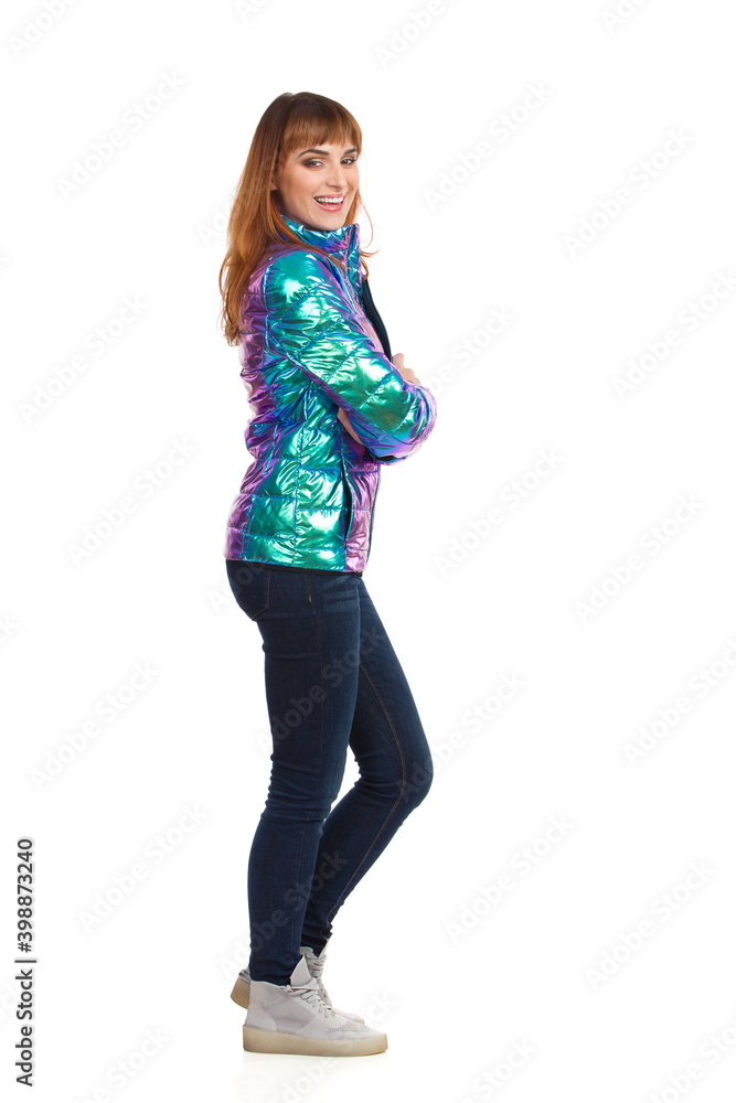 Laughing Young Woman In Winter Clothes Standing With Arms Crossed And Looking At Camera. Side View. Laughing Young Woman In Winter Clothes Standing With Arms Crossed And Looking At Camera. Side View.