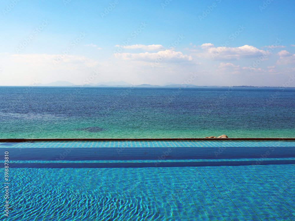 sea view swimming pool, blue green ocean and bright blue sky with clouds