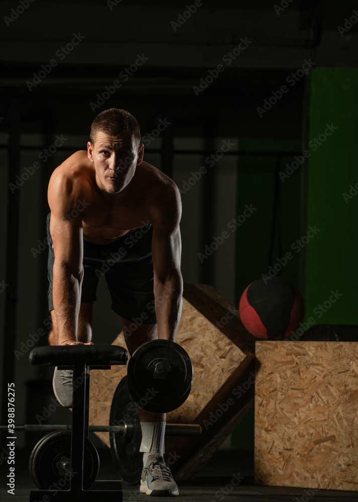 Sportsman doing exercises with weights over fitness bench and looking straight at the camera. Sportsman doing exercises with weights over fitness bench and looking straight at the camera.
