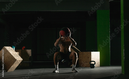 Fit man throwing medicine ball doing ball slam against gym floor or shoulder press exercise.. © qunica.com