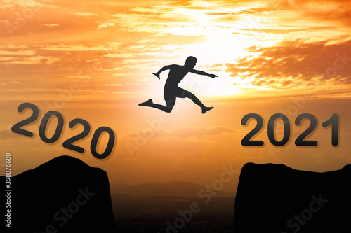 2021 New year concept : Silhouette man jumping from year 2020 to new year 2021