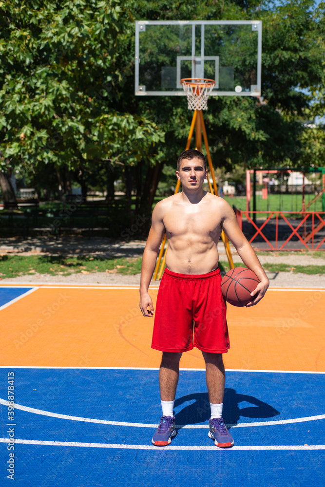 Naklejka premium Portrait of young basketball player on a streest court.