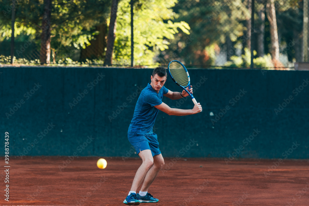 Professional equipped male tennis player beating hard the tennis ball with a backhand