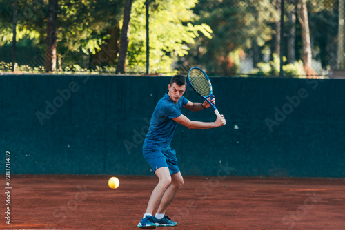 Professional equipped male tennis player beating hard the tennis ball with a backhand