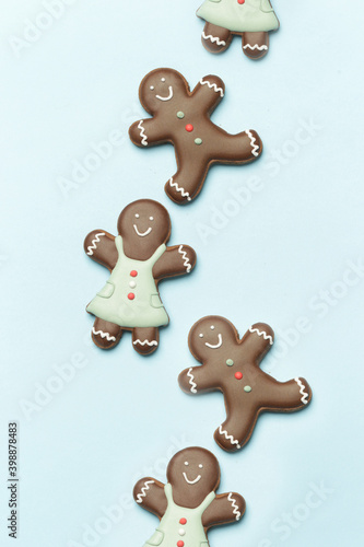 Beautiflly decorated gingerbread cookies on wintery blue background. Tasty homemade Christmas cookies close up view. 