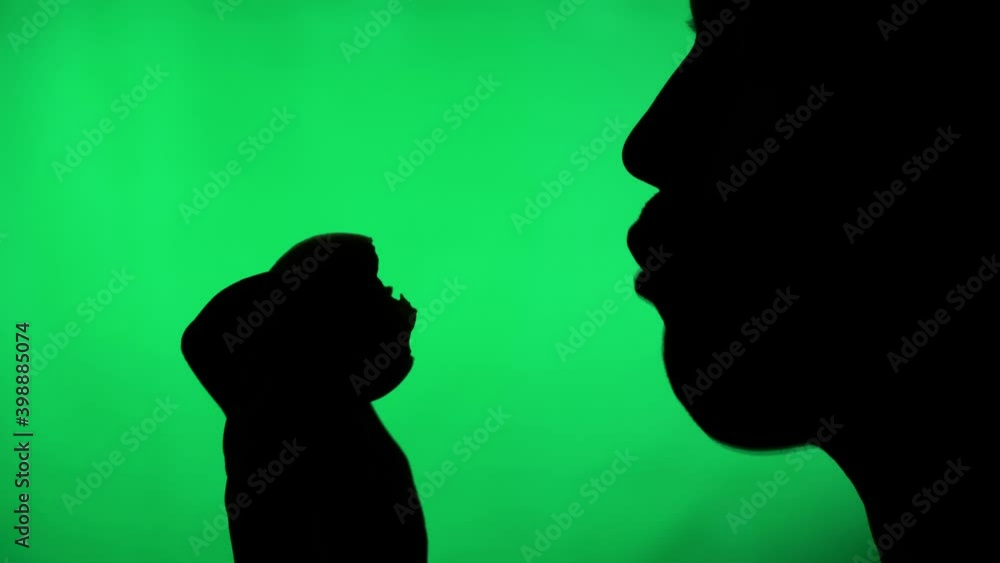 silhouette of a person on a green background. man bites and eats fruit or vegetables silhouette of a person on a green background. man bites and eats fruit or vegetables
