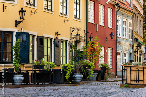 Medieval street with colourful houses  lanterns and plants in Riga Old Town during sunny autumn day is empty of tourists