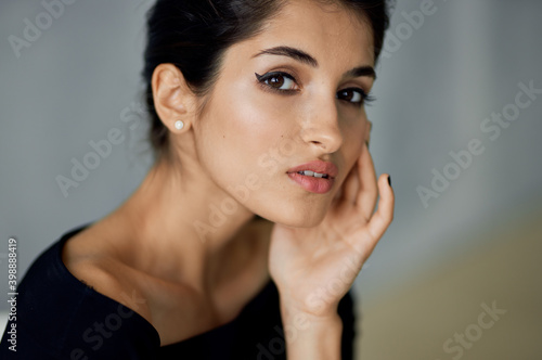 beautiful Lydia With evening make-up in a black dress sits indoors on a chair