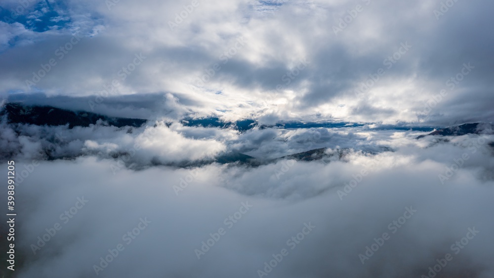 Obraz premium Flight through blue sky with clouds over mountain