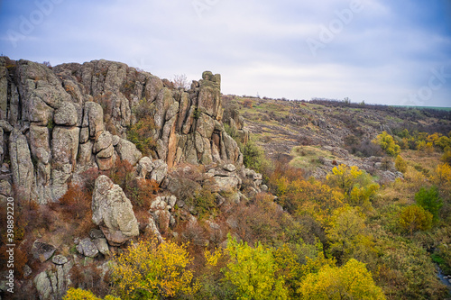 A picturesque stream flows in the Aktovsky Canyon, surrounded by autumn trees and large stone boulders photo