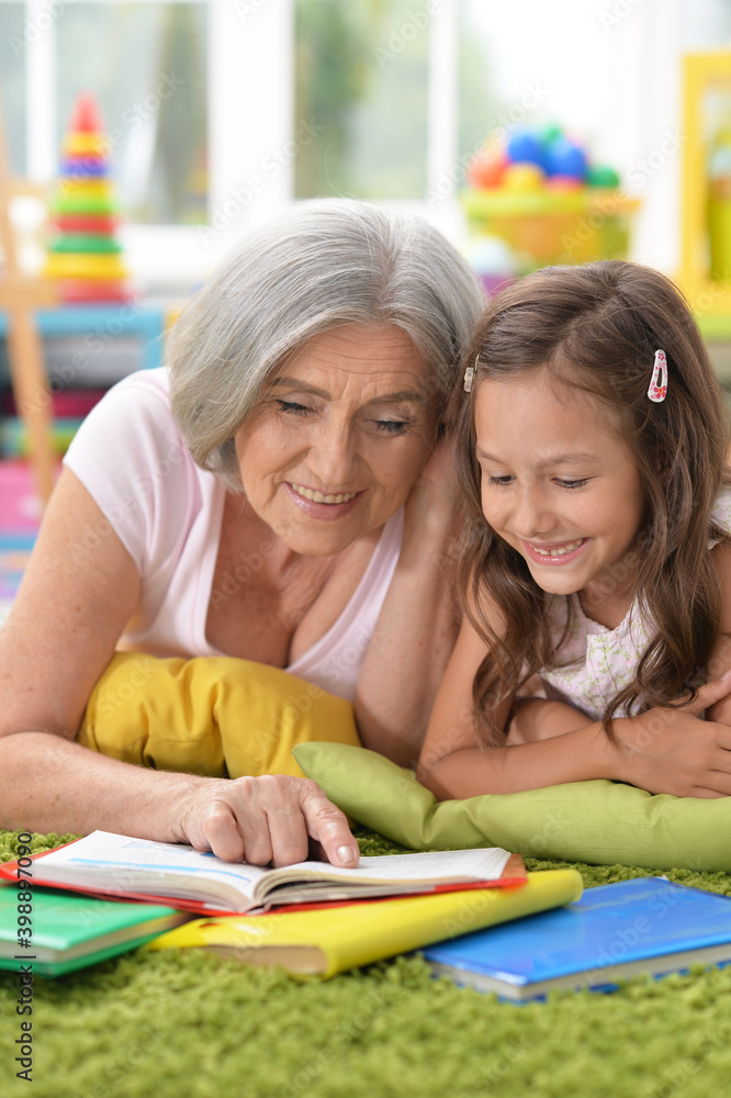 Grandmother reading book with her little granddaughter