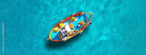 Aerial top view photo of traditional fishing boat anchored in turqoise bay and beach of Balos, Chania, Crete, Greece