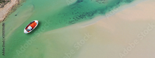 Aerial top view photo of traditional fishing boat anchored in turqoise bay and beach of Balos, Chania, Crete, Greece photo