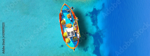 Aerial drone top view ultra wide panoramic photo of traditional wooden fishing boat anchored in crystal clear turquoise sea of Antipaxos island, Ionian sea, Greece © aerial-drone