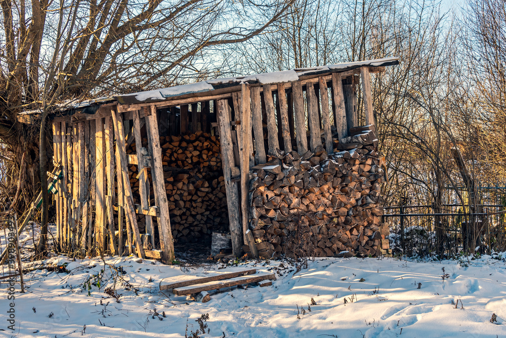 An old rickety shed where firewood is kept. Rural scene. Winter.